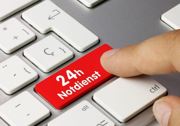Finger drückt eine rote Taste mit der Aufschrift 24h Notdienst